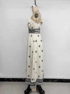 Detail of bohemian cream maxi dress featuring intricate black geometric embroidery