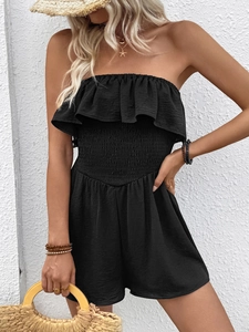 Detailed close-up of smocked waist and ruffled neckline on black summer jumpsuit