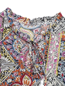 Détail de l'encolure en V à volants avec imprimé paisley et cordons à pompons blancs