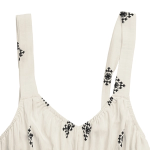 Detail of bohemian embroidery and breathable fabric on a cream summer maxi dress