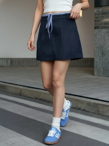 Close-up of a navy blue A-line mini skirt featuring a checkered drawstring waist tie