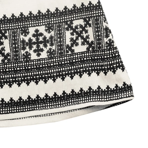 Close-up of geometric ethnic pattern and print detail on a white summer midi dress