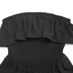 Close-up of black strapless jumpsuit featuring ruffle neckline and elastic smocking detail