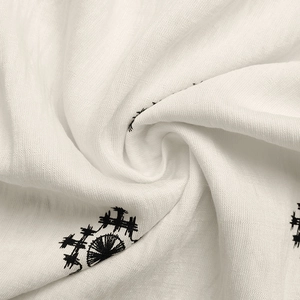 Detailed macro shot of breathable white cotton fabric with black geometric embroidery patterns
