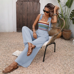 Detail of bohemian light blue jumpsuit with colorful geometric embroidery and shoulder ties