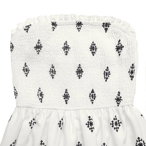 Détail d'une robe bustier blanche froncée avec motif losanges noirs et volants