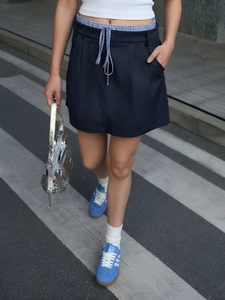 Detail of navy blue A-line skirt with plaid waistband ties and city street fashion style