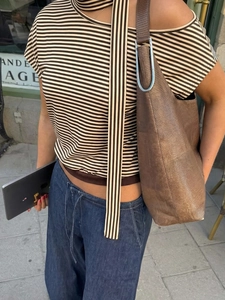 Détail d'un haut à rayures dénudé avec un sac cabas marron texturé et un pantalon denim