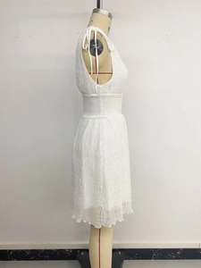 Detail of white sleeveless dress showing textured pleated fabric and tie-up shoulder straps