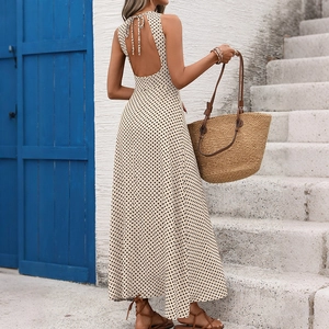 Détail d'une robe maxi dos nu à pois avec lien à nouer devant une porte bleue
