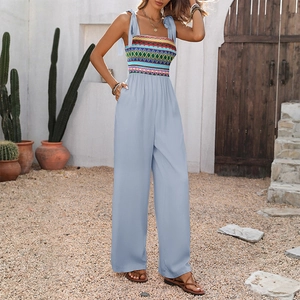 Detail of light blue wide-leg jumpsuit with colorful ethnic embroidery and bow straps