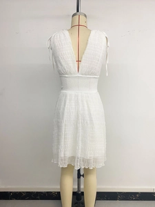 Detail of white V-neck dress featuring pleated texture and shoulder drawstring ties