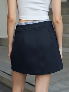 Detail view of the dark mini skirt with blue plaid waistband detail and slim fit design