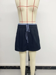 Detail of black A-line skirt with blue plaid patchwork waistband and drawstring ties