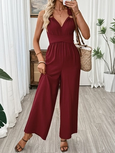 Detail of burgundy wide-leg jumpsuit showing elegant crisscross waist and drape texture