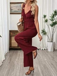 Detail of burgundy cross back jumpsuit with deep V-neck and pleated waist texture