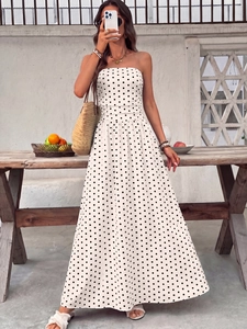 Close-up of white strapless maxi dress with black polka dots and flowing pleated skirt