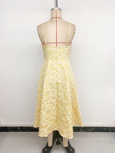 Detail of light yellow jacquard floral fabric and open back on elegant midi summer dress