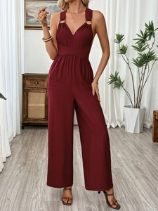 Detail of cross waist cut and deep V-neck on a burgundy backless wide-leg jumpsuit