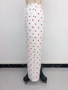 Dettaglio di pantaloni larghi bianchi con stampa a cuori rossi e vita elastica con coulisse