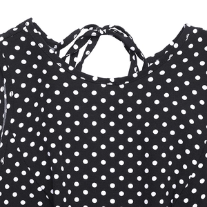 Gros plan sur le lien de cou élégant et le motif à pois blancs sur une robe noire