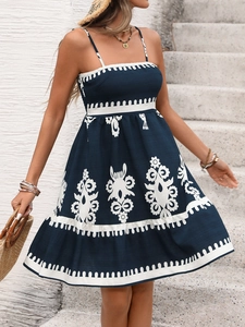 Detailed embroidery and ruffle hem of a navy blue bohemian sundress in summer sunlight
