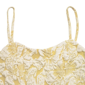 Close-up of yellow floral jacquard fabric texture and thin shoulder strap of the dress