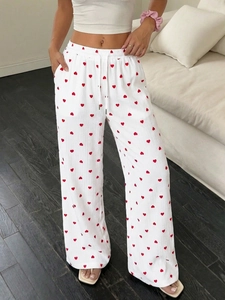 Dettaglio dei pantaloni bianchi a gamba larga con cuori rossi e vita elastica con coulisse