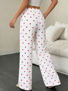 Dettaglio dei pantaloni bianchi a gamba larga con motivo a cuore e tessuto a nido d'ape