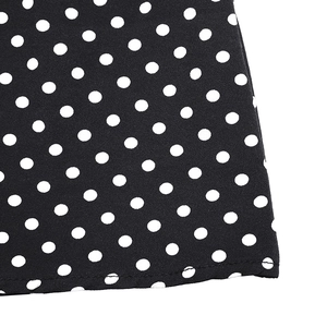Gros plan détaillé sur l'imprimé à pois blancs et l'ourlet piqué de la robe d'été noire