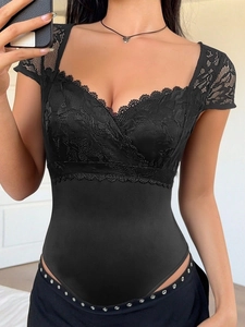 Dettaglio del body in pizzo nero con motivi floreali e scollatura a V con bordo smerlato