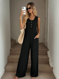 Detail shot of black sleeveless jumpsuit with golden buttons and large side pockets