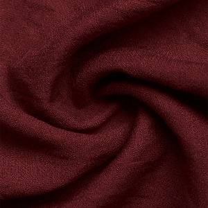 Detailed close-up of dark red fabric showing fine texture and elegant soft draping