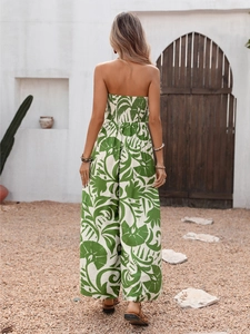 Detail of white strapless jumpsuit featuring tropical green leaf print and smocked back