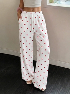 Dettaglio dei pantaloni bianchi a gamba larga con cuori rossi e coulisse in vita