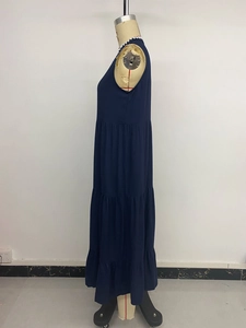 Détail d'une robe maxi bleu marine à volants avec bordure ondulée blanche sur l'encolure