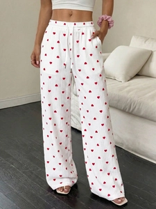 Dettaglio dei pantaloni larghi bianchi con stampe a cuori rossi e coulisse in vita