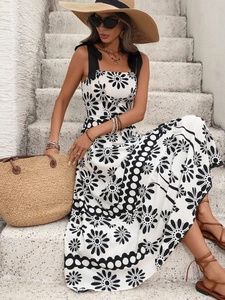 Detail of floral sundress with black ribbon shoulder ties and daisy print on white fabric