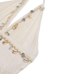 Détail du col en V avec coquillages naturels et paillettes argentées sur robe beige