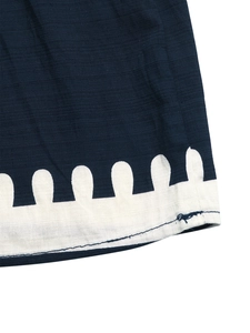 Detail of navy blue linen fabric hem with white wave embroidery and fine stitching
