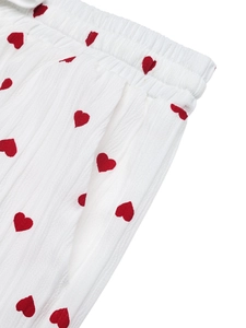 Dettaglio dei pantaloni larghi plissettati bianchi con cuori rossi ed elastico