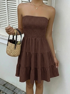 Detail showing the smocked bodice and tiered texture of a brown strapless summer dress