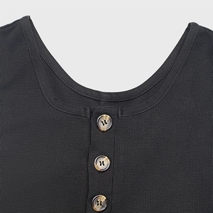 Detailed macro view of black waffle texture knit neckline with three tortoiseshell buttons