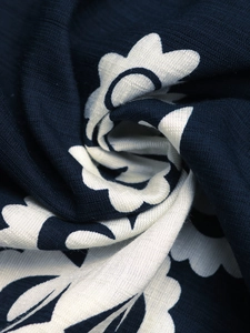 Macro shot of dark blue and white fan-shaped floral print on textured woven fabric