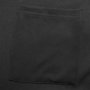 Close-up of black waffle knit fabric featuring a square patch pocket and neat stitching