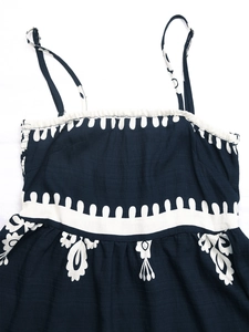 Detailed close-up of navy blue smocked dress with white floral print and adjustable straps