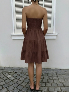Detail of smocked elastic back on a brown strapless tiered summer dress with tiered layers