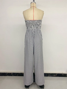 Back view of a smocked striped jumpsuit with black and white vertical pattern on a mannequin