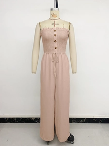 Detail of pink smocked strapless jumpsuit featuring decorative front buttons and drawstring