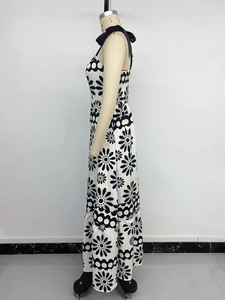 Detail of summer halter dress with black floral print and tiered ruffle hemline